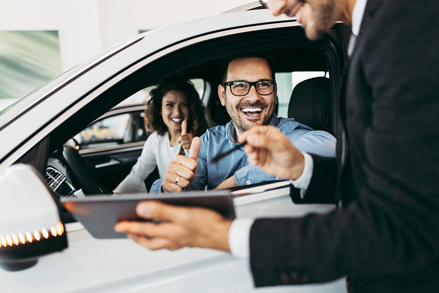Couple sitting inside a car at a dealership